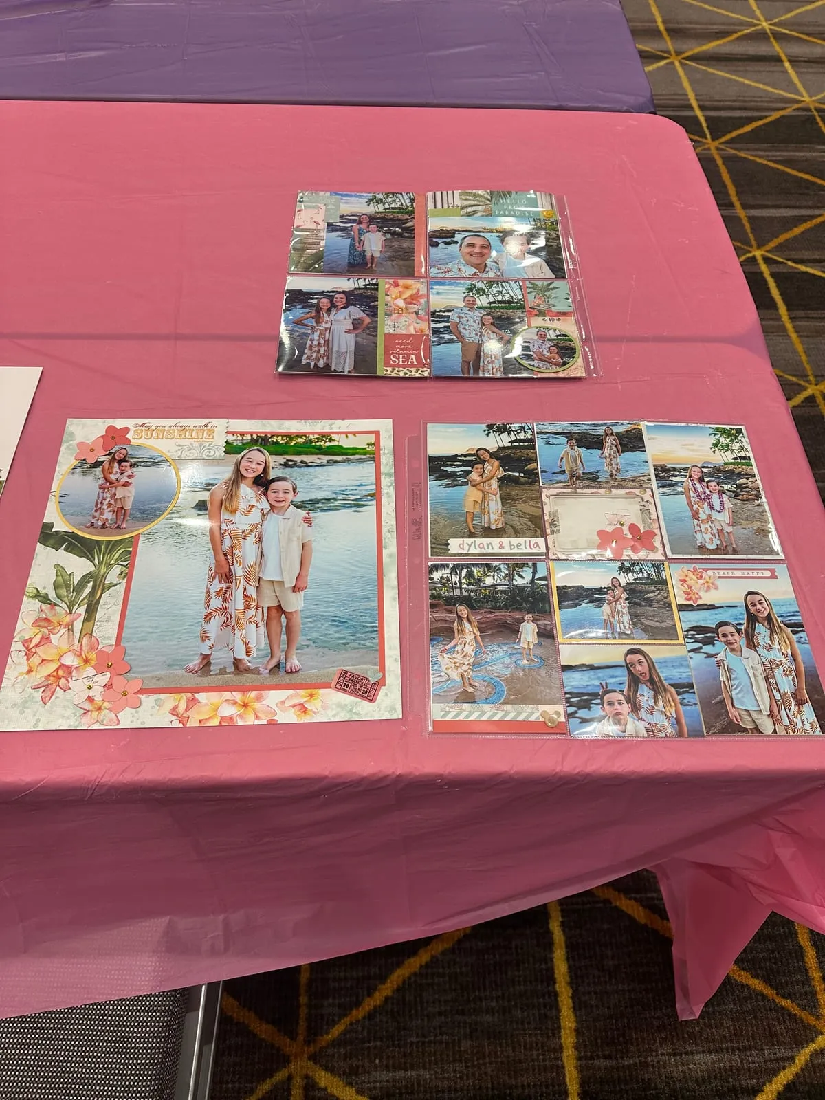 Finished pages on a pink table: a Hawaii beach layout with plumeria embellishments beside two pocket-page spreads of family photos