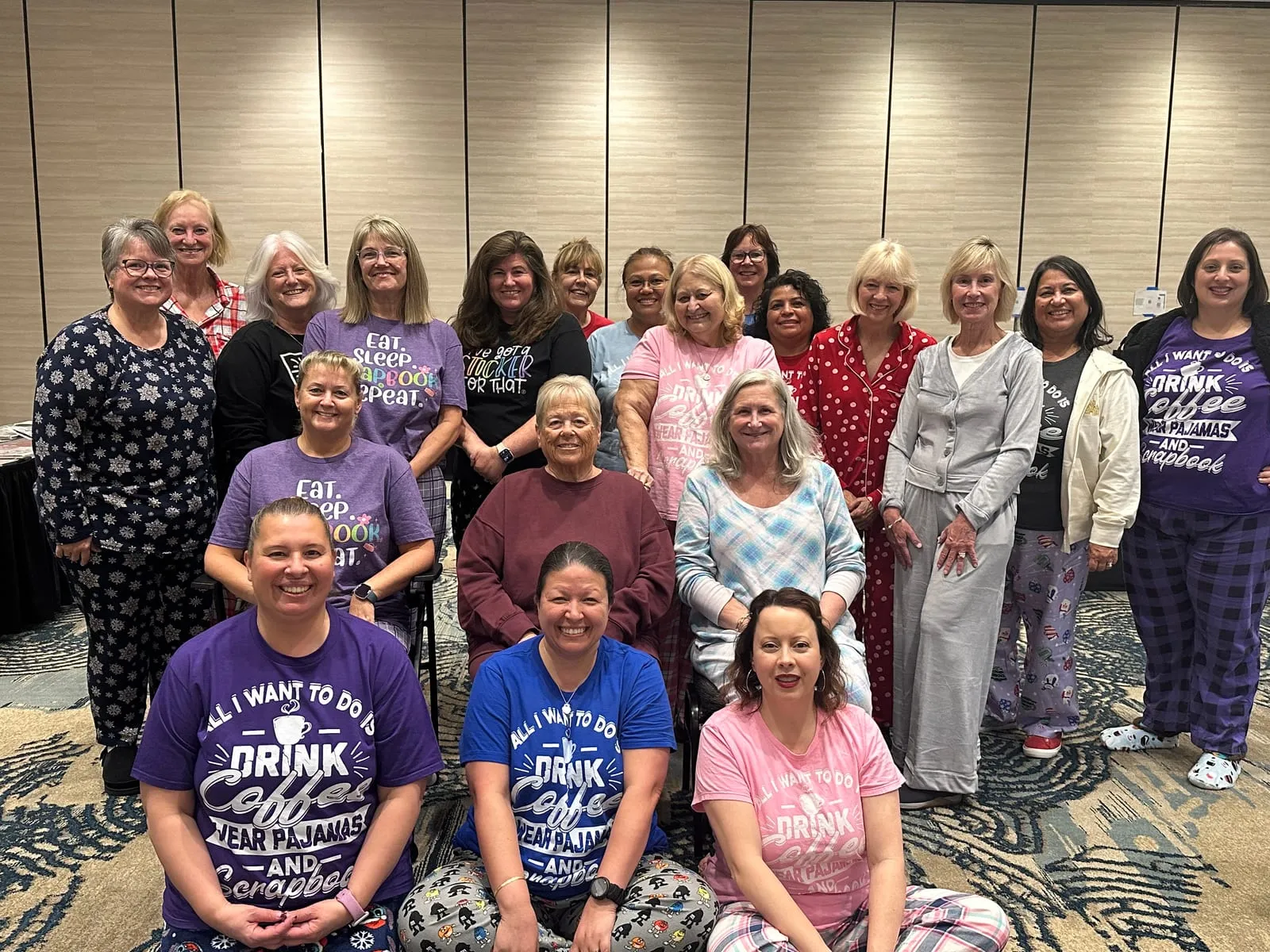A crop’s pajama party: two dozen retreat-goers in matching “drink coffee, wear pajamas and scrapbook” shirts posing for a group photo
