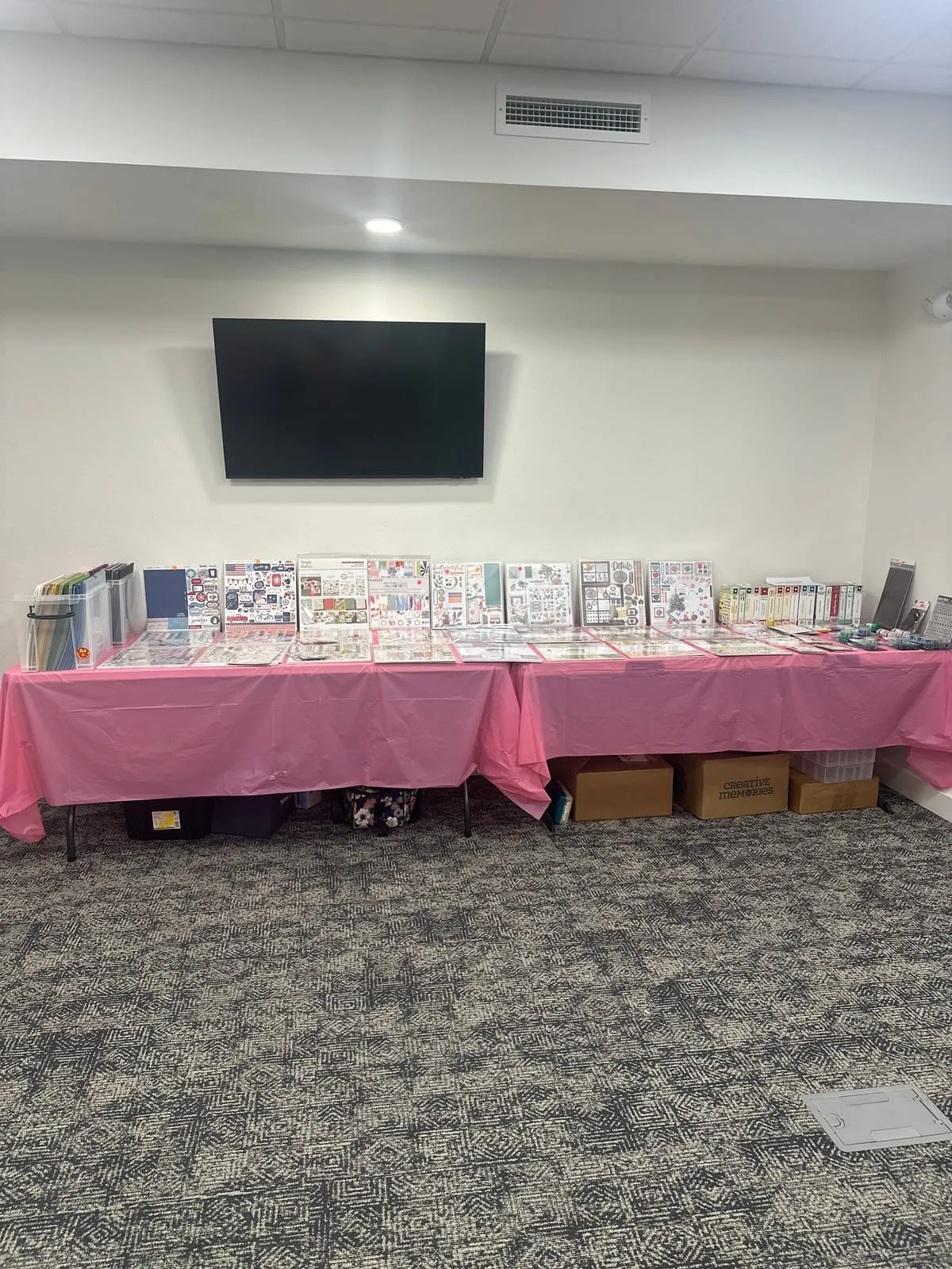 The on-site store: two pink-draped tables lined with paper collections, sticker sheets and album kits